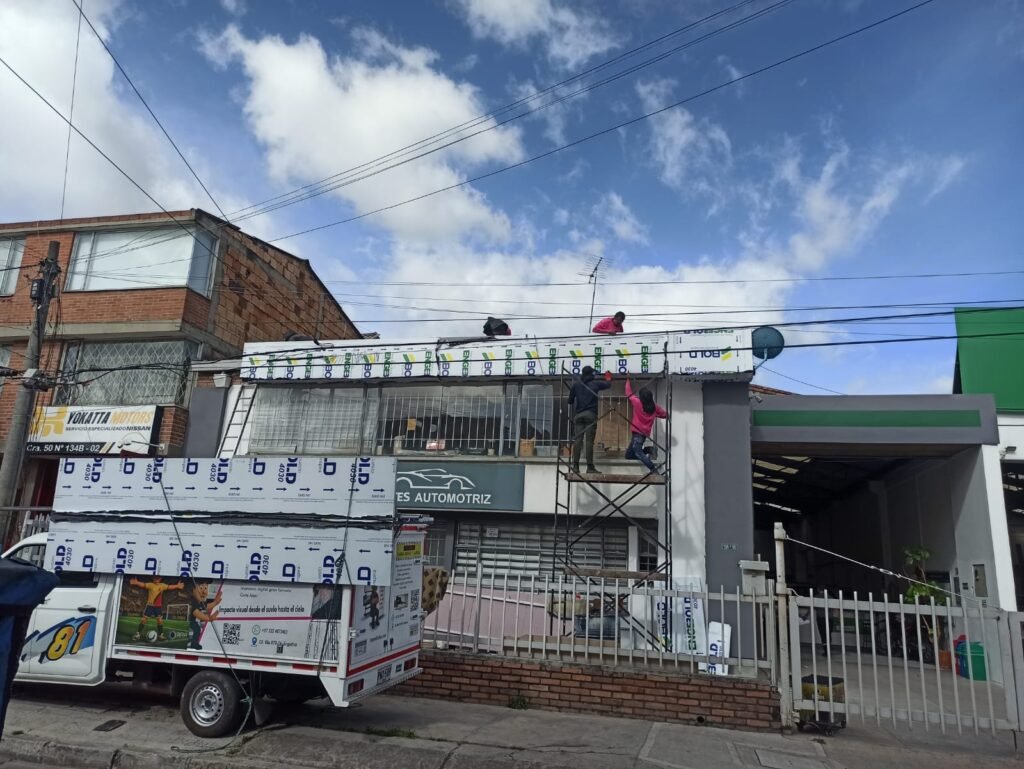 Equipo técnico de BRA Publicidad instalando un aviso en aluminio compuesto (ACM) sobre la fachada de un establecimiento comercial utilizando andamios y técnicas profesionales de montaje.