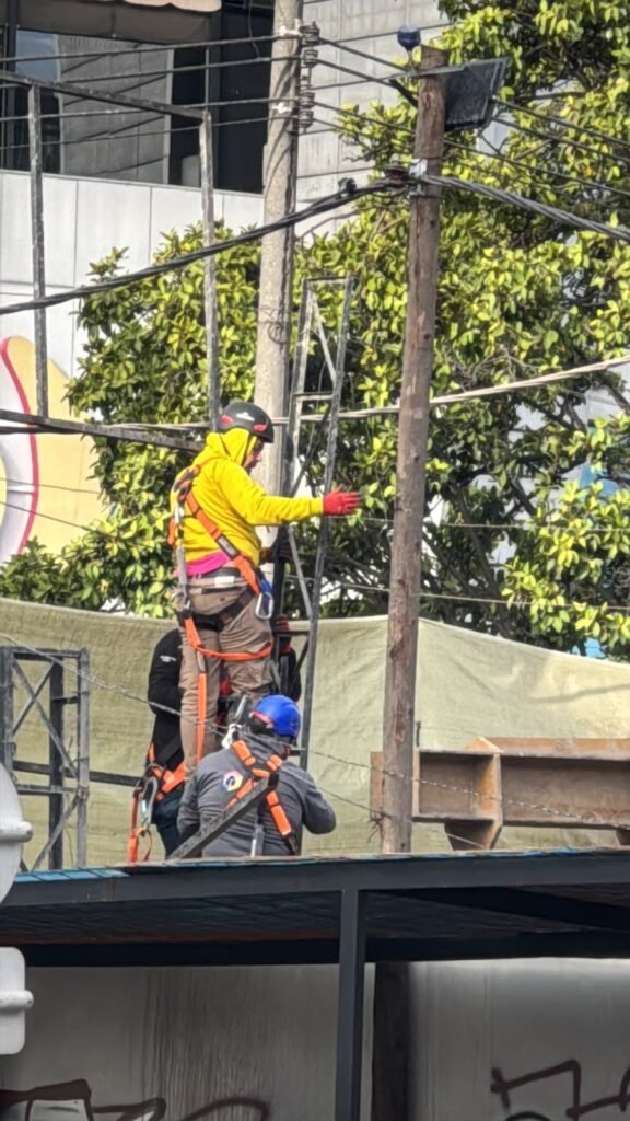 Técnicos de BRA Publicidad realizando la instalación de una estructura publicitaria en trabajo seguro en alturas utilizando arnés, casco, línea de vida y equipos de protección personal.