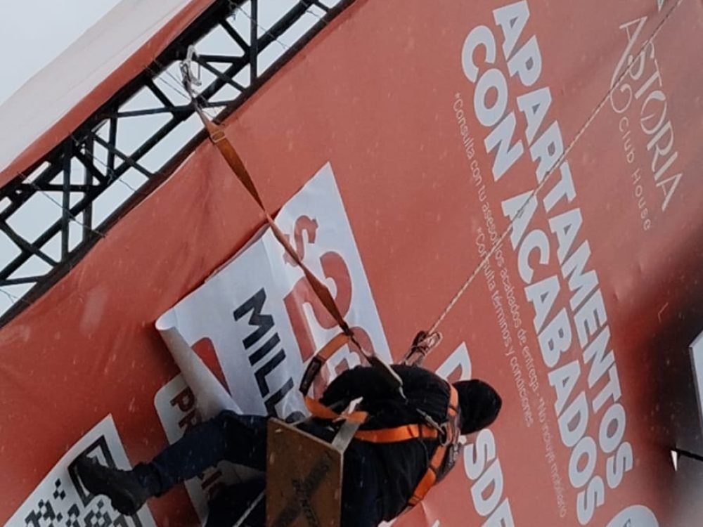 Perspectiva lateral de la instalación segura de banner publicitario en estructura metálica de gran altura, realizada por el equipo de BRA Publicidad SAS.